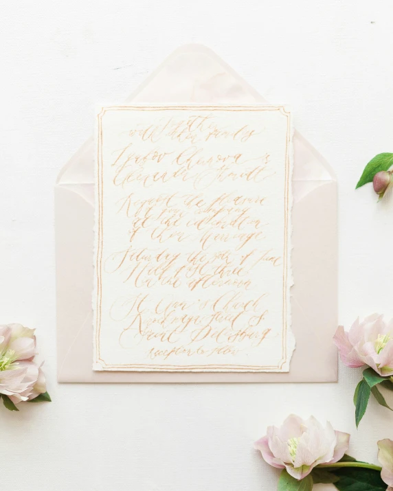 pink and gold wedding stationery featuring calligraphy and floral envelope