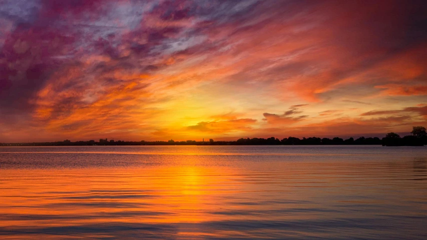 the sun rises above the water with an orange and red sky