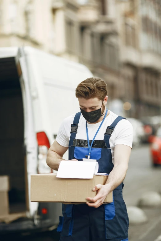 a man standing next to a moving truck holding a box