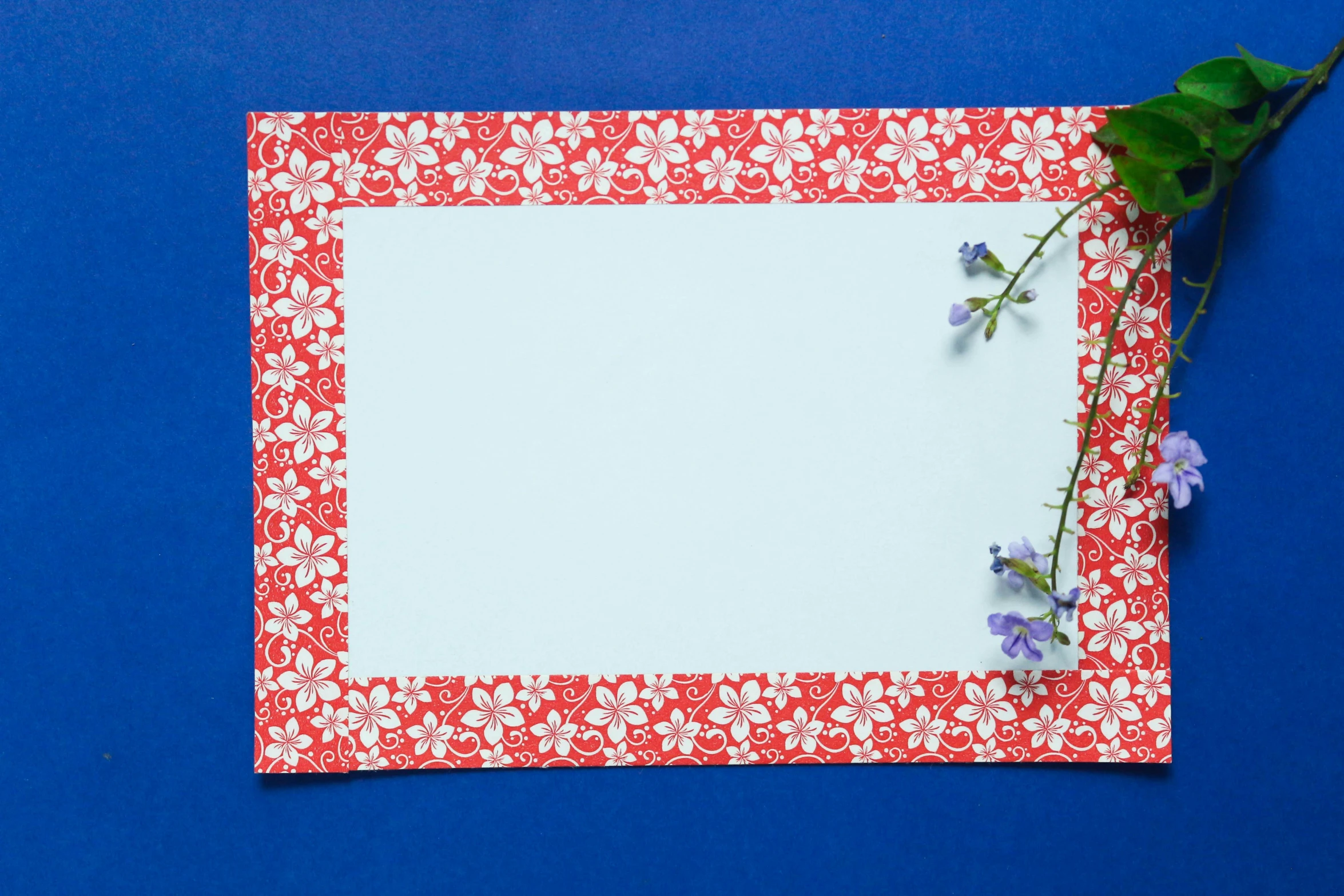 a red, white and pink floral pattern paper next to some green leaf