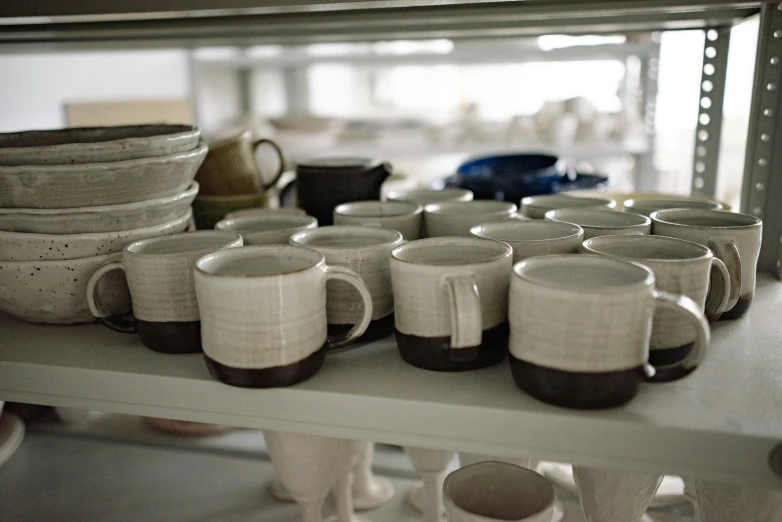 various white and gray cups and saucers sitting on a shelf