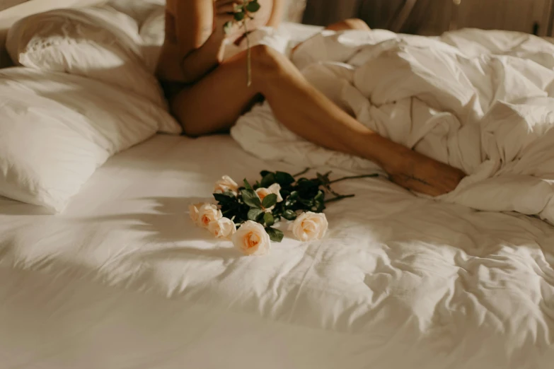 a woman laying in bed with flowers and a bouquet