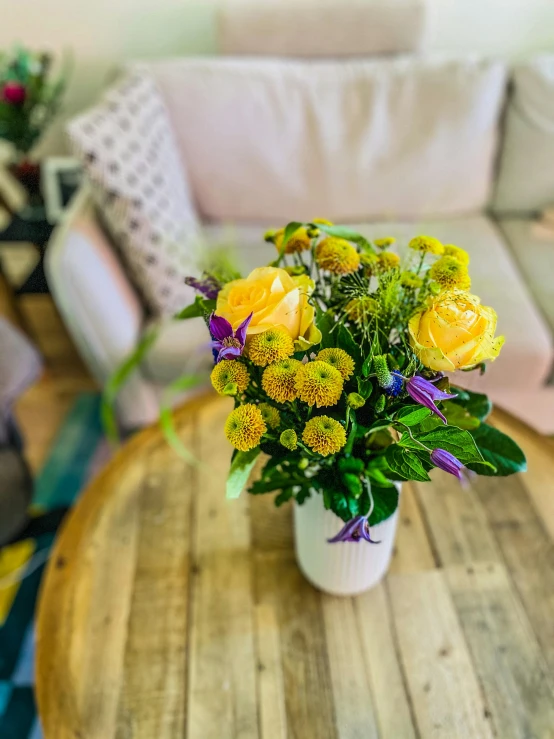 yellow roses and green plants on a wood table