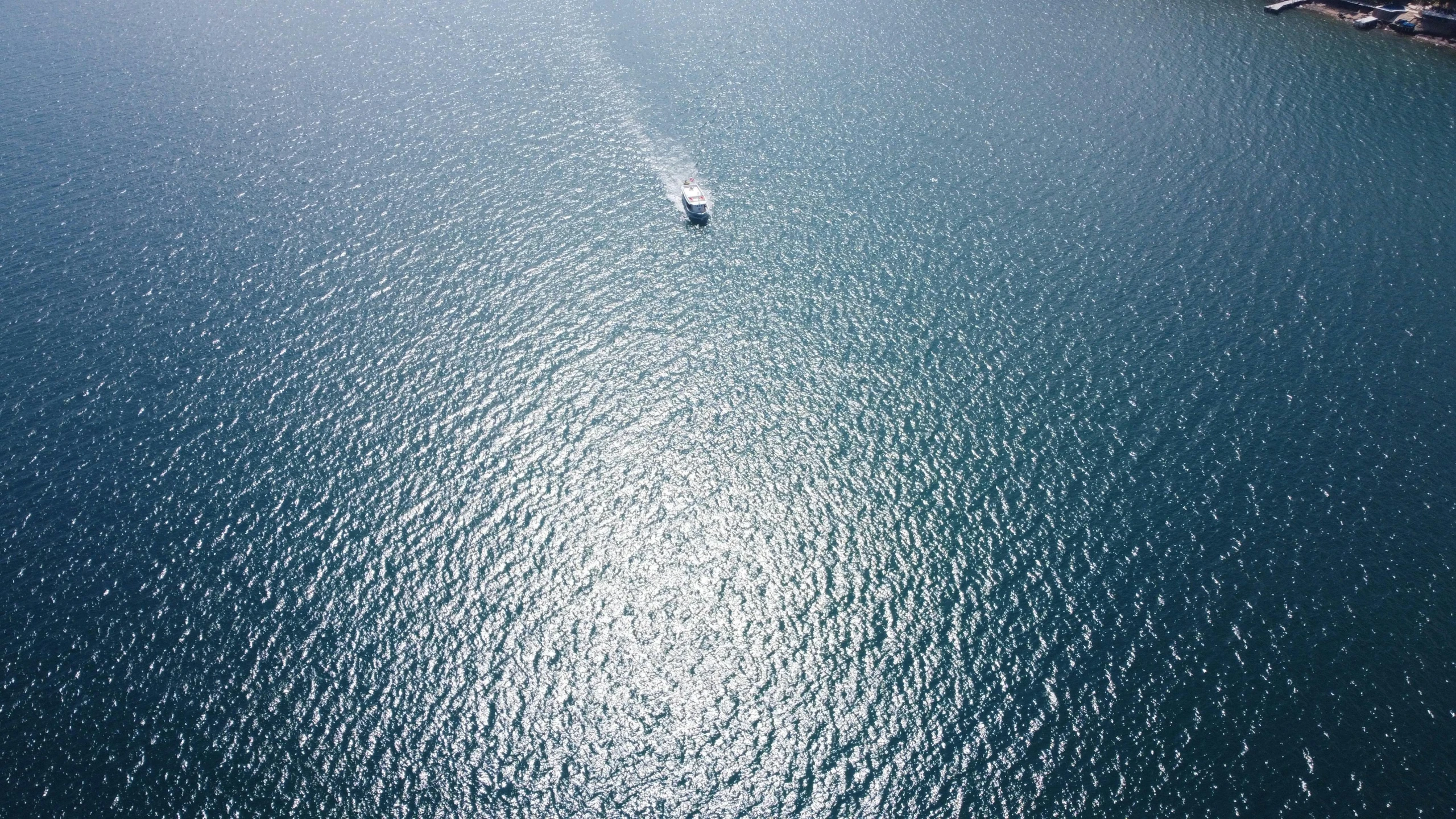 a small boat glides across a beautiful, blue sea