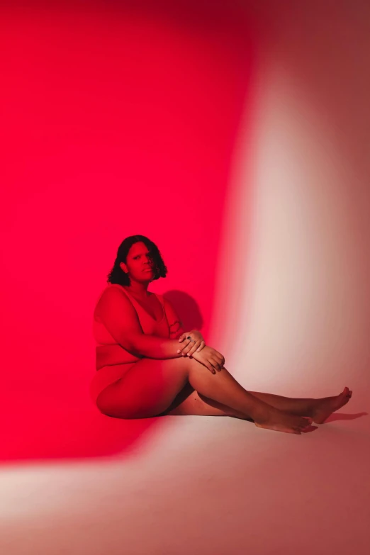 an image of a woman sitting on the floor in a red room