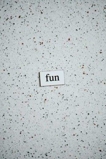 a tiny piece of paper that says fun next to brown speckles