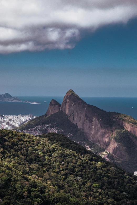 a city is seen beyond the green mountains