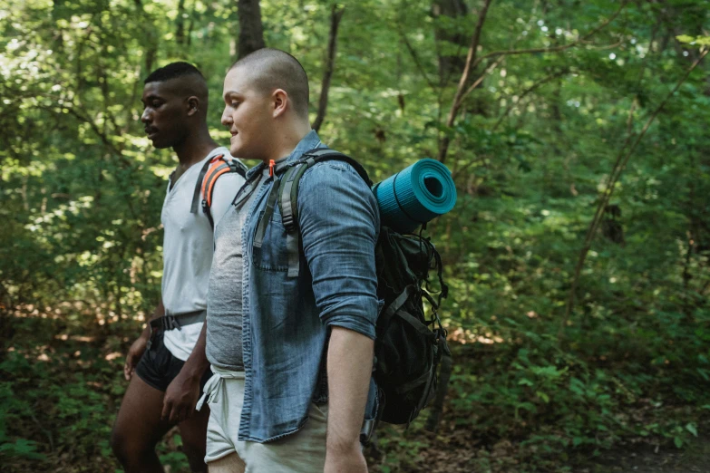 two people carrying different kinds of items near some trees