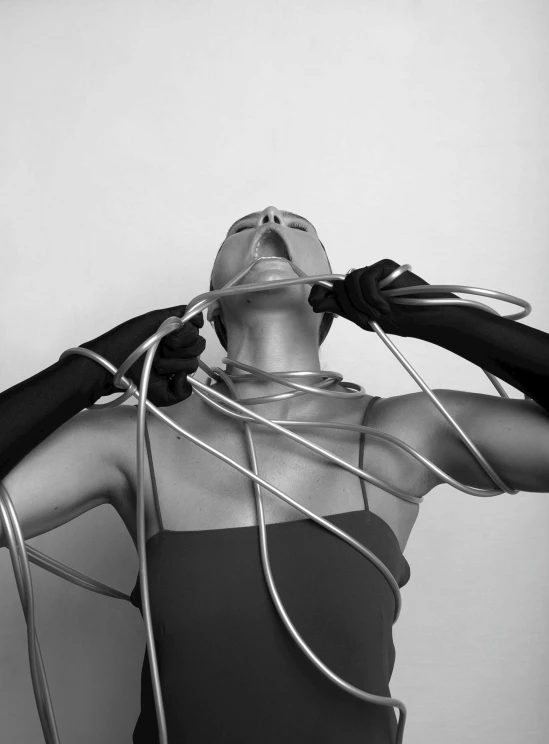 black and white pograph of a woman in tight clothing tied with silver strings