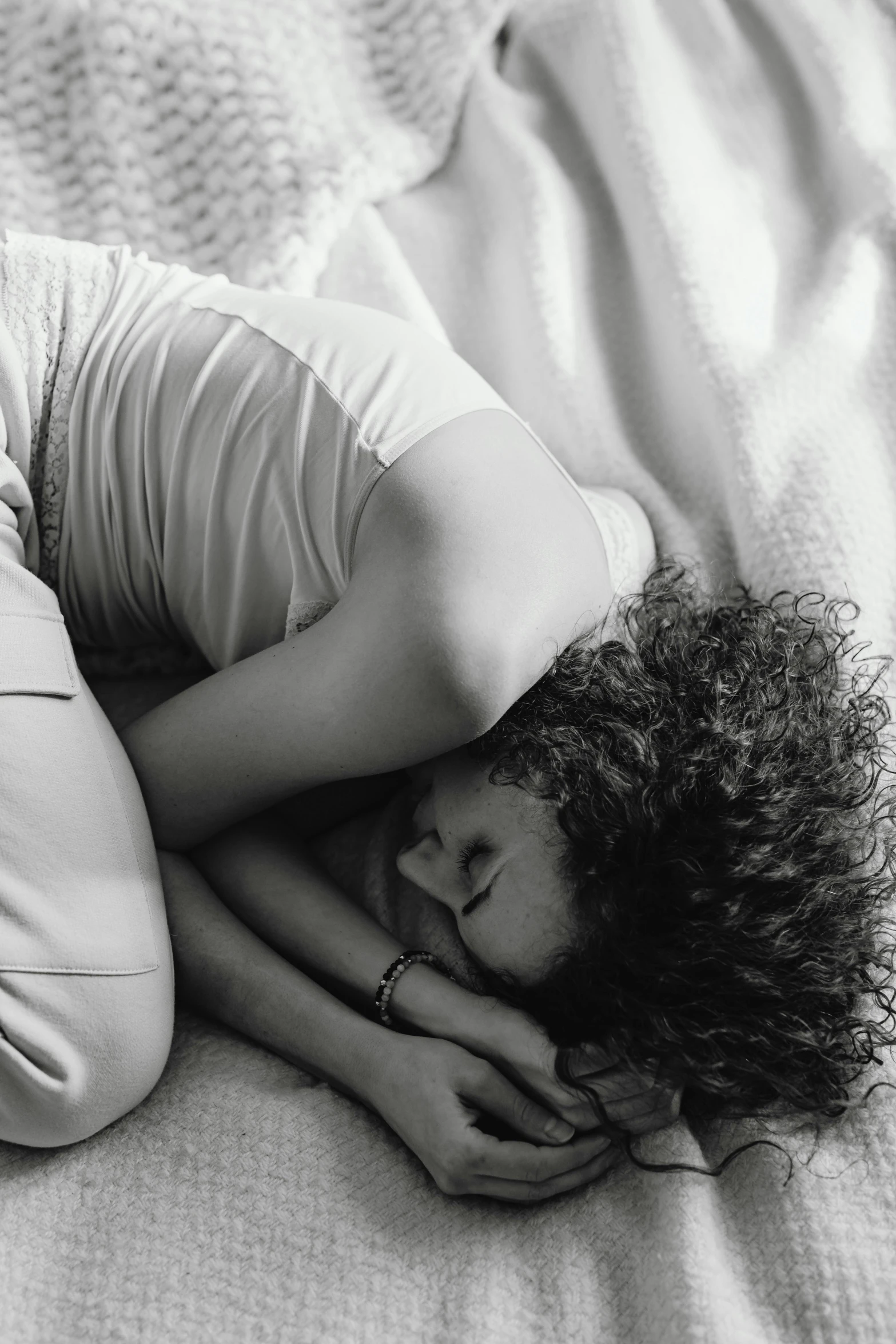 a woman lying on the floor in a bed, with her head on her knees