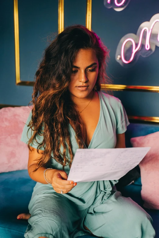 a beautiful woman sitting on top of a bed holding a piece of paper