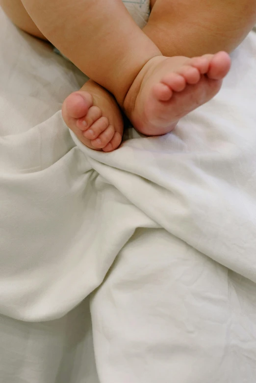 a baby laying on a bed next to an open book