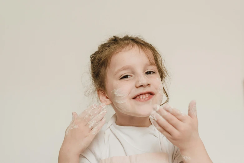 a girl smiles as she brushes her hands with cream