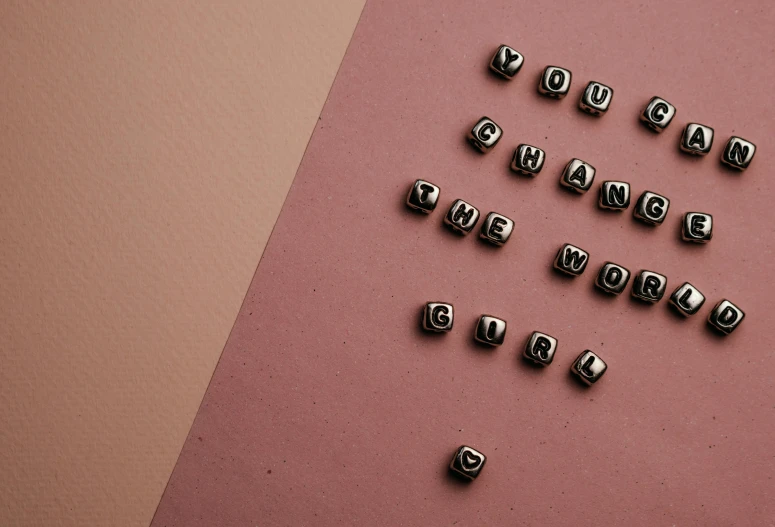 metal beads arranged on pink surface, with letters