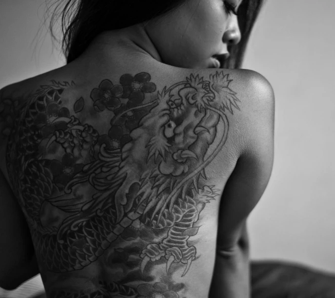 a girl is covered in tattoos on her back