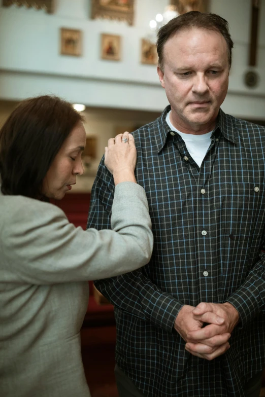 man helping woman adjust the armband of another man