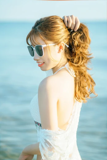 a woman with long hair and sunglasses standing on a beach