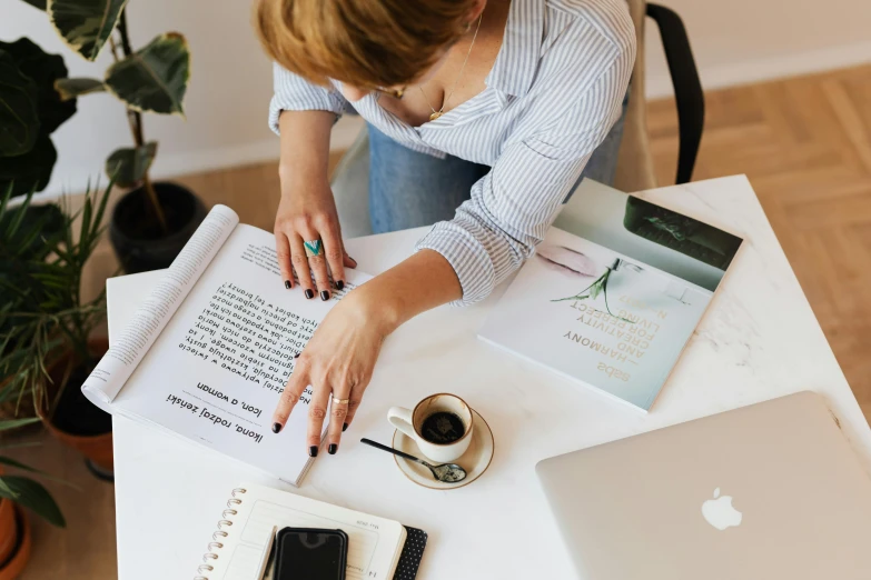 a woman is writing on a notebook while holding a pen