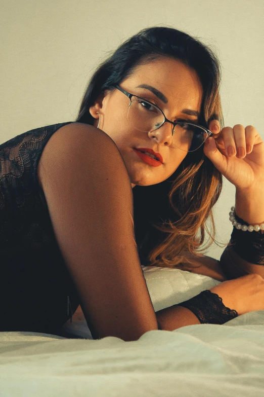 a girl in glasses is lying on her bed