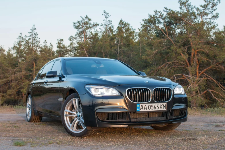 a black car parked in front of a forest