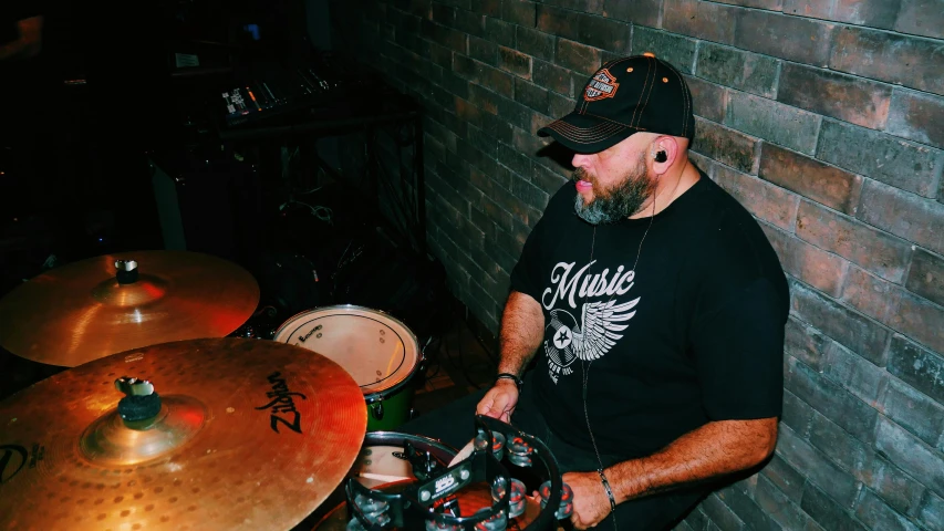 man with beard and red cap playing drums