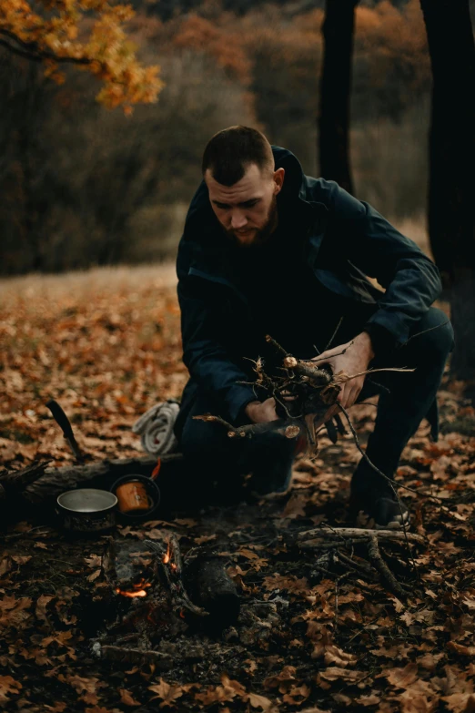 a man is crouched over an outdoor fire pit