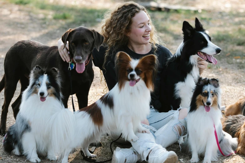 a woman is posing with many dogs in the field