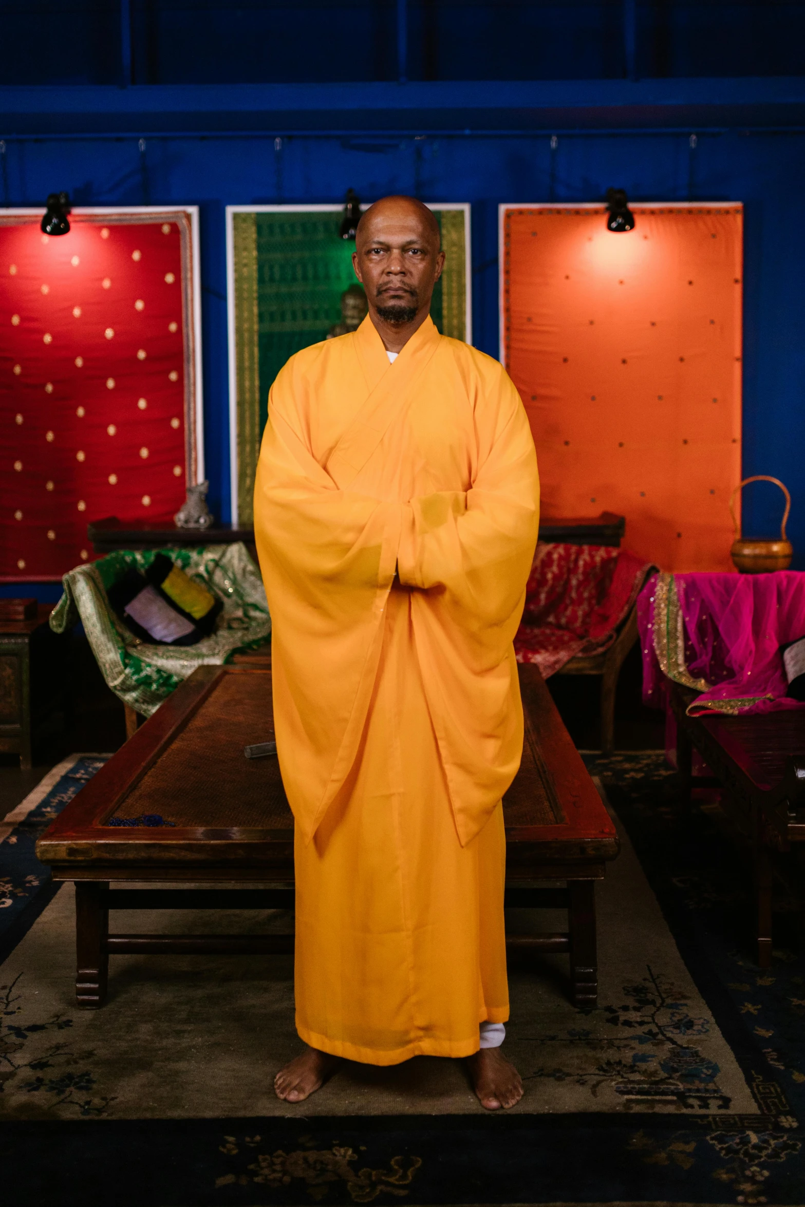 the man is dressed in an orange robe and stands