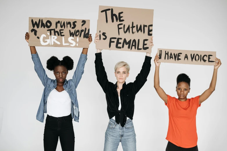 three females with signs that read the three women, the fight against female power