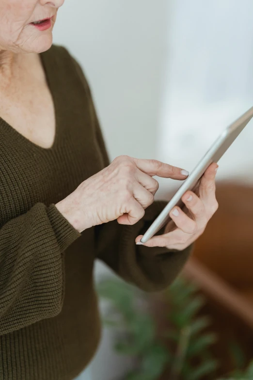 an older woman is holding up a tablet