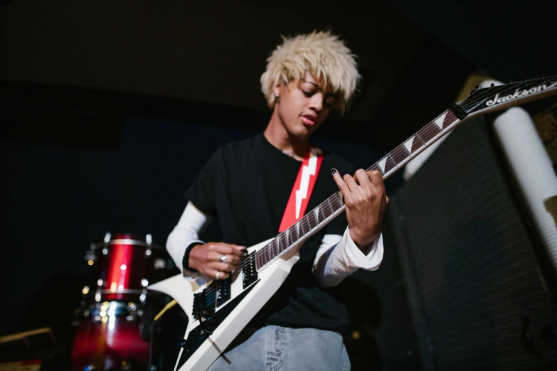 man with blonde hair playing guitar in room