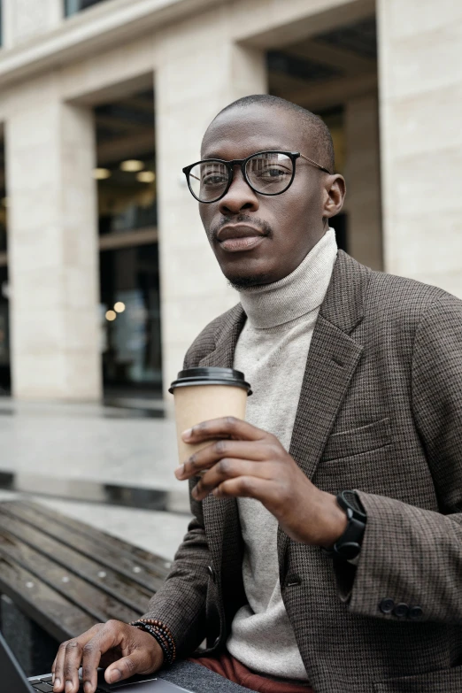 a black man in glasses is holding a coffee cup