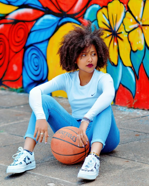 young woman playing basketball in front of a painted wall