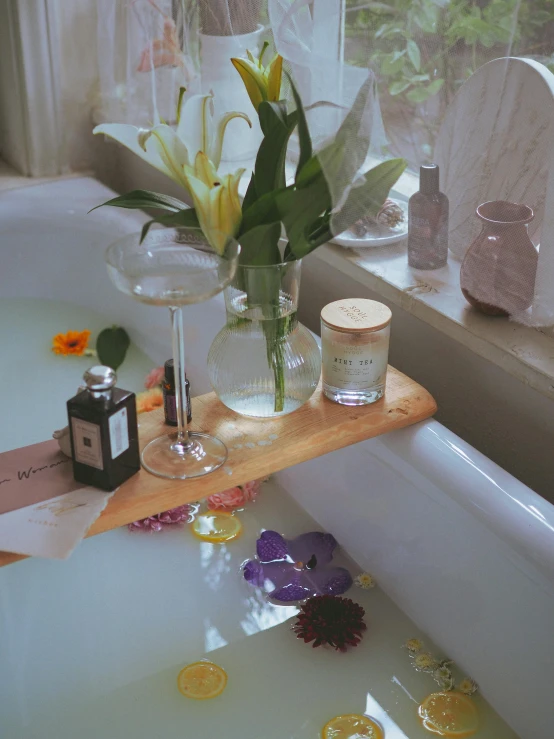 flowers in a clear vase sitting on top of a bathtub next to coins