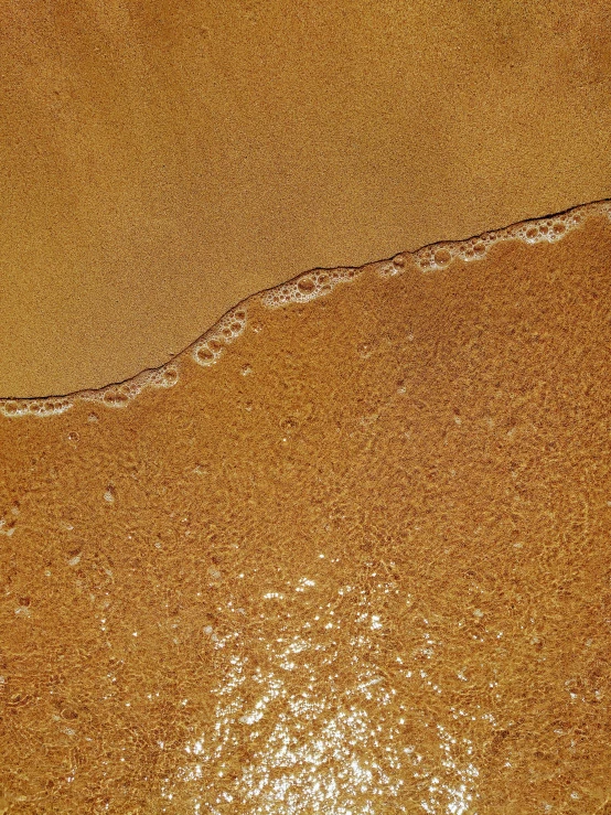 aerial view of beach with brown sand, sea and surf