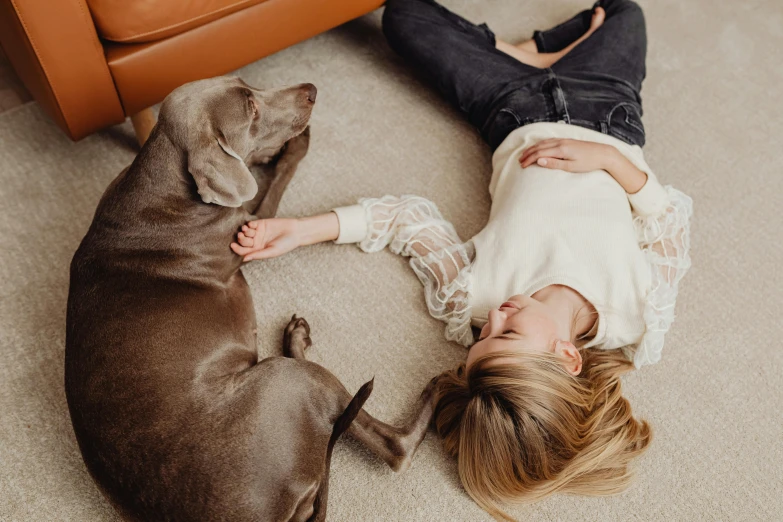 a beautiful young woman laying on the floor next to a dog