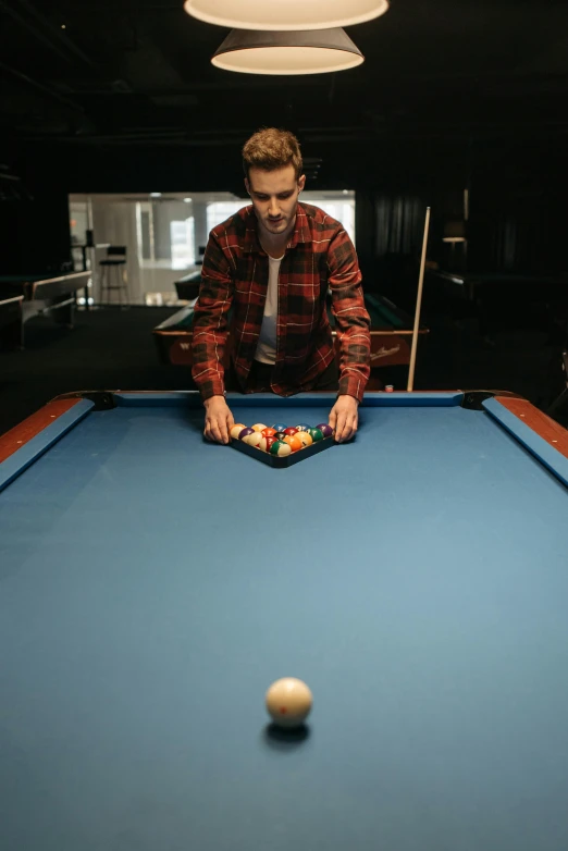 a young man is playing pool and preparing to hit a ball