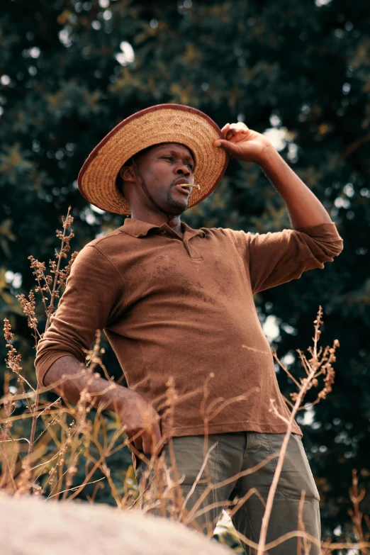 a man in a straw hat is standing near some grass