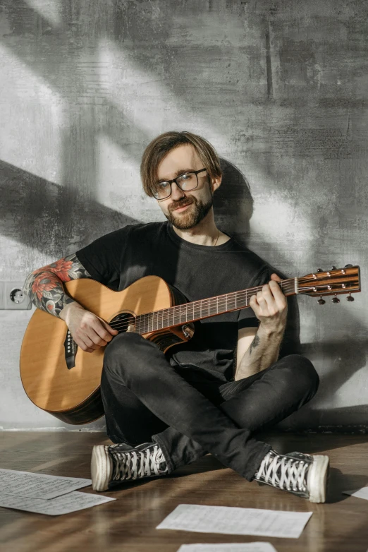 a man that is sitting on the ground with a guitar