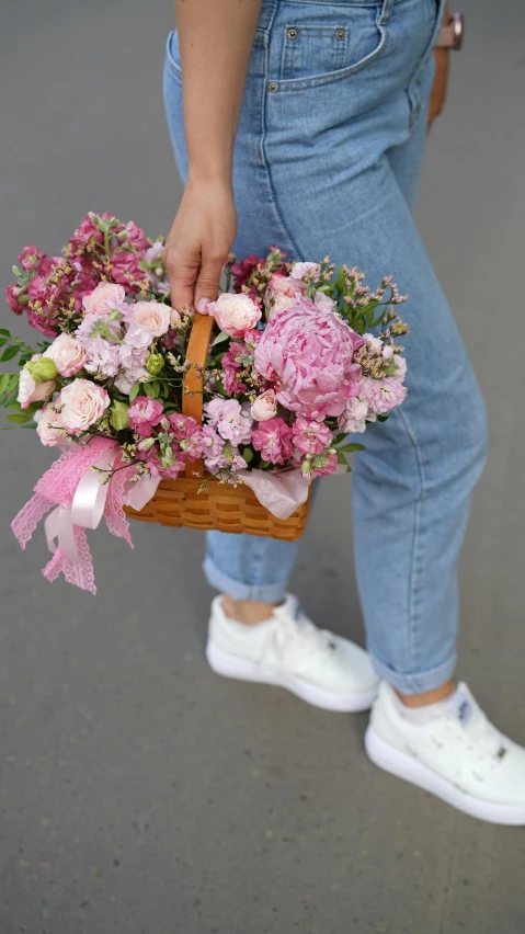 a person holding flowers in a basket on the street