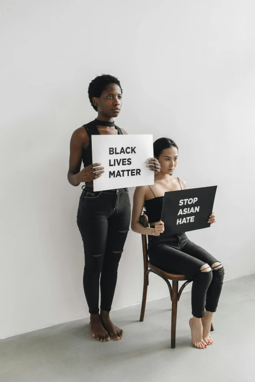 two girls are standing next to each other holding black lives matter signs