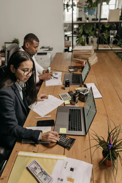 three people sitting at a table working on laptops