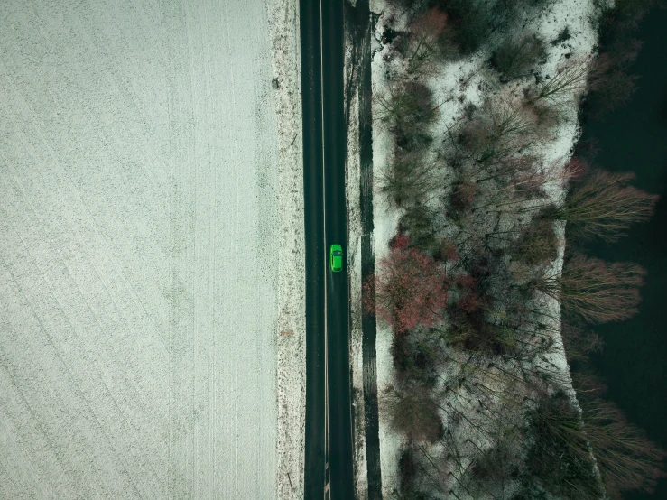 two roads in a snowy landscape with a green car
