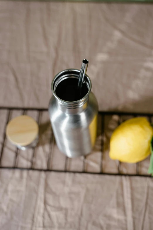 a table with a metal mug and a lemon and a spoon