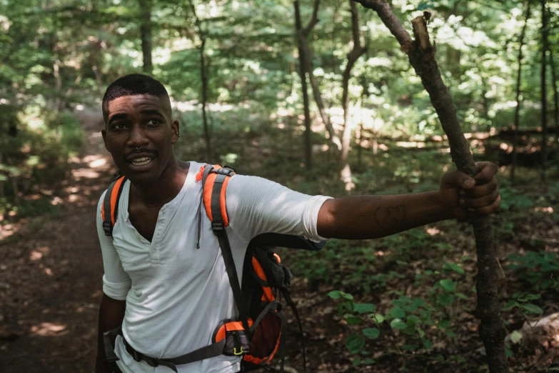 the man smiles while holding his back against a tree nch