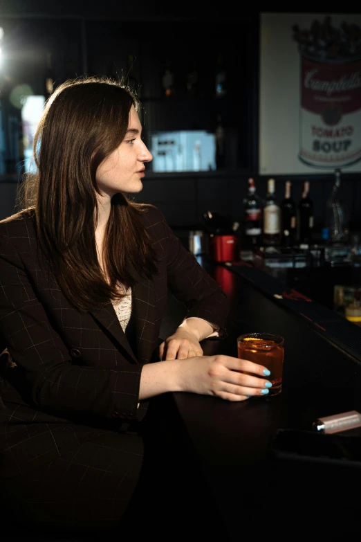 a young woman wearing a black jacket and holding a coffee mug