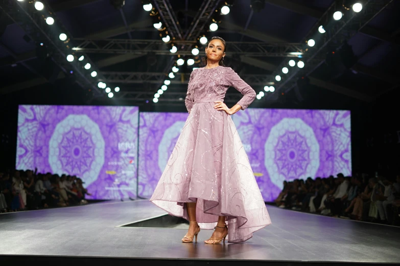 woman in dress on runway with purple patterned backdrop