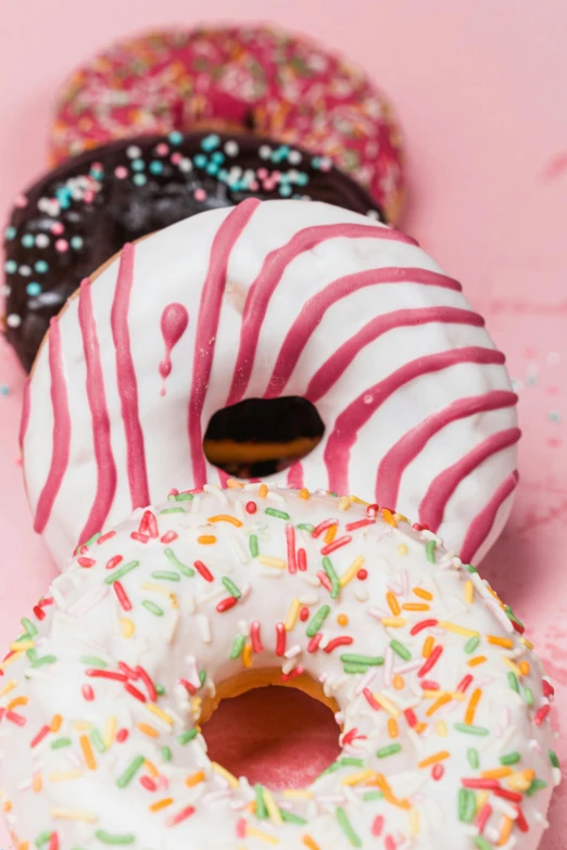 five donuts in striped and pink with sprinkles