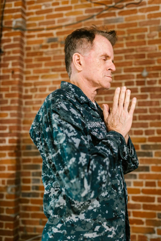 a soldier in camouflage holds his hands together