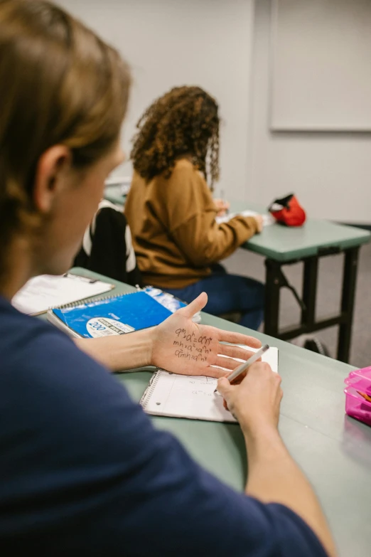 a lady with writing on her hand in a classroom